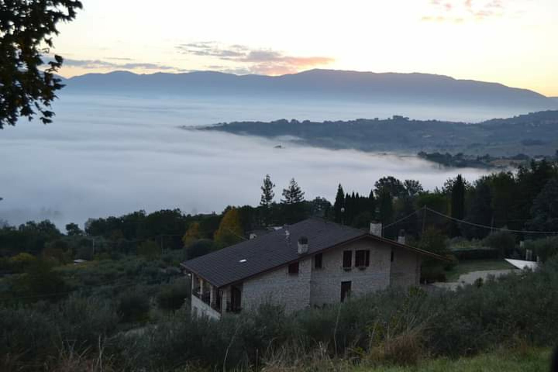 L'agriturismo all'alba sopra la nebbia della valle umbra