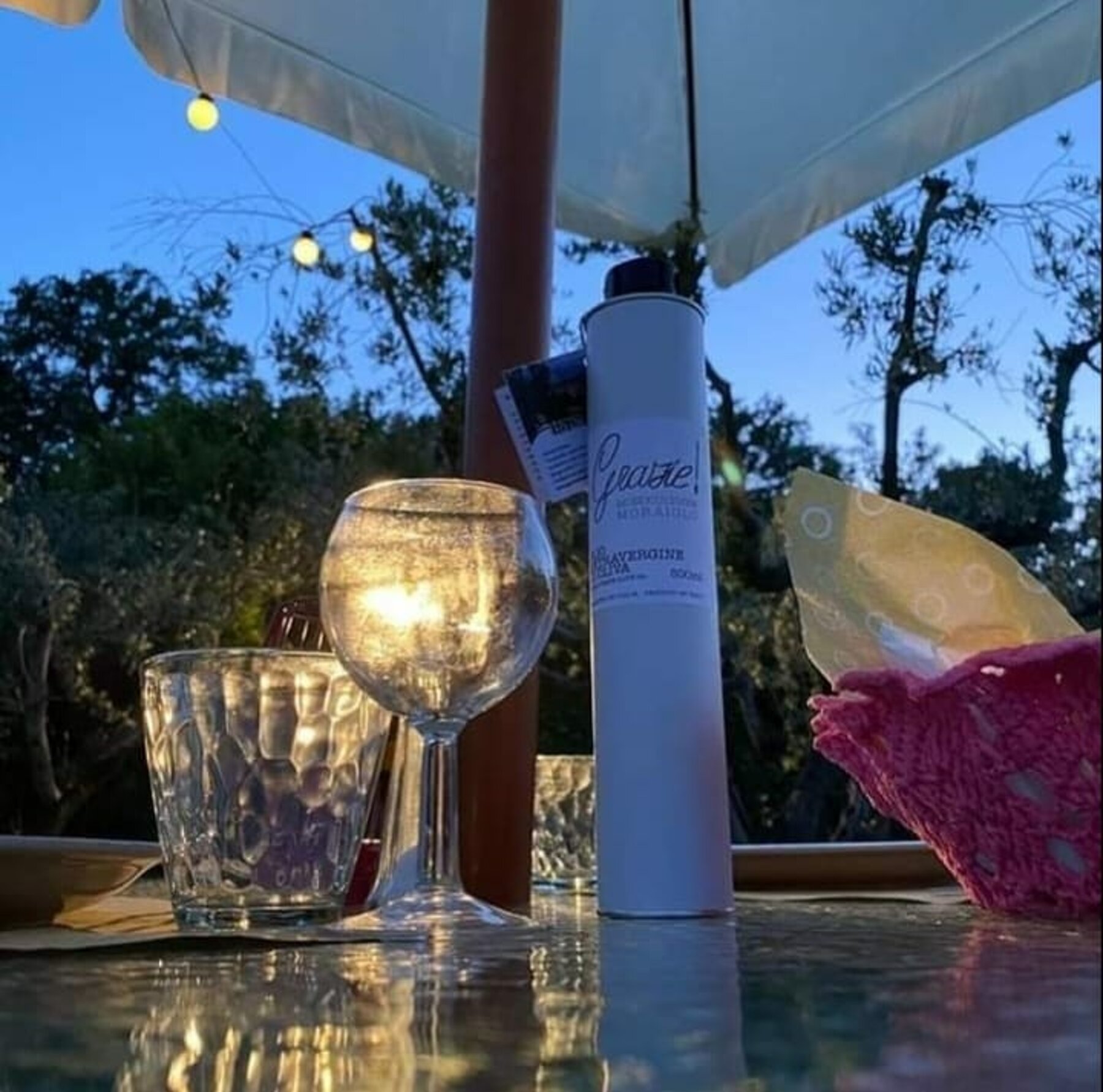 Un calice e l'olio Grazie! su un tavolo all'aperto al tramonto